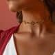 Detalle del cuello de una modelo luciendo el choker dorado Fabiana con piedras azules caladas y pendientes colgantes.