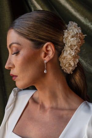 Perfil lateral de una modelo con recogido bajo luciendo los pendientes plateados Estefanía con estrella brillante y perla colgante.