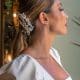 Perfil lateral de una modelo con coleta baja pulida decorada con el tocado de tres hileras de perlas Natalia colocado de lado.
