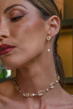 Primer plano de perfil de una modelo luciendo los pendientes dorados Ambas con detalle de perla y recogido bajo.